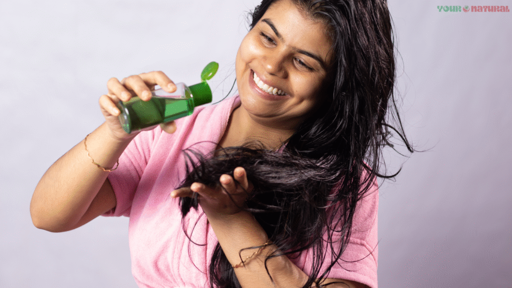 Woman applying onion hair oil to her wet hair while smiling